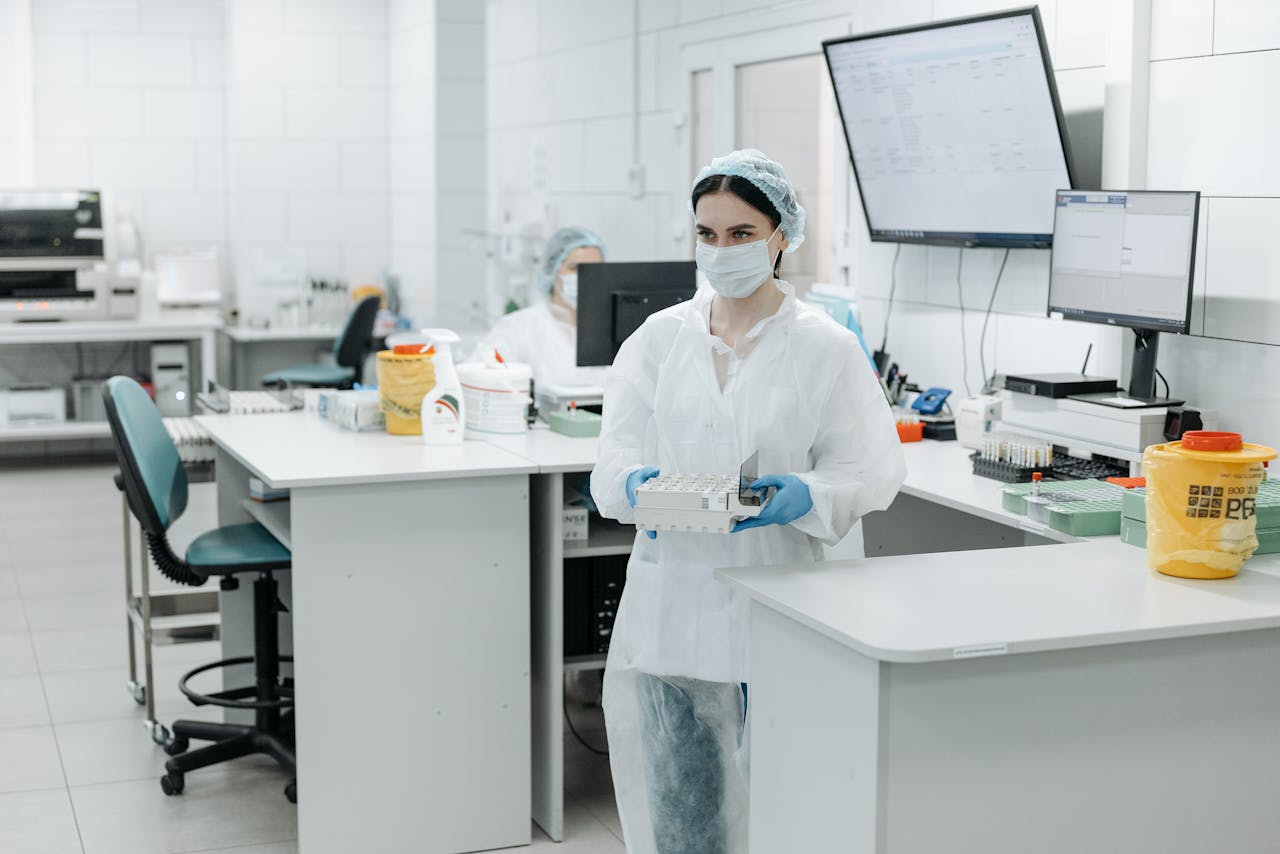 services-04 Female scientist wearing PPE working in a modern laboratory with test samples.