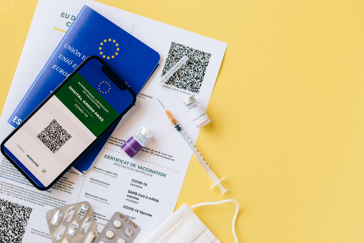 Digital vaccine passport and COVID-19 vaccination items including syringes and masks on a yellow background.